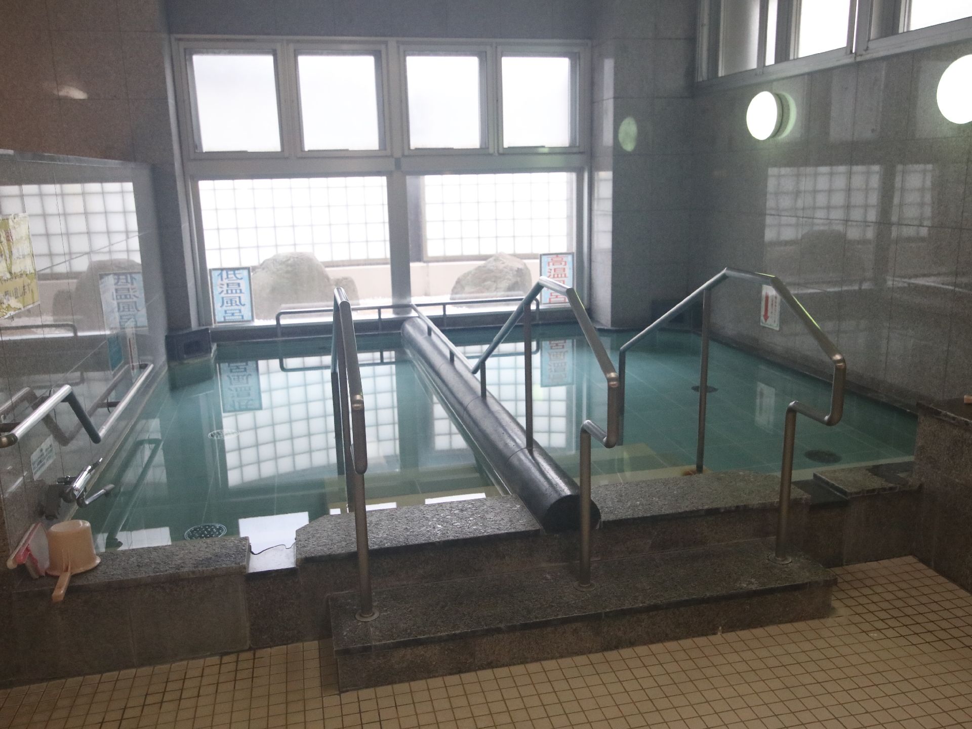 大きな窓の前の大きな浴槽に伸びる銀色の手すり