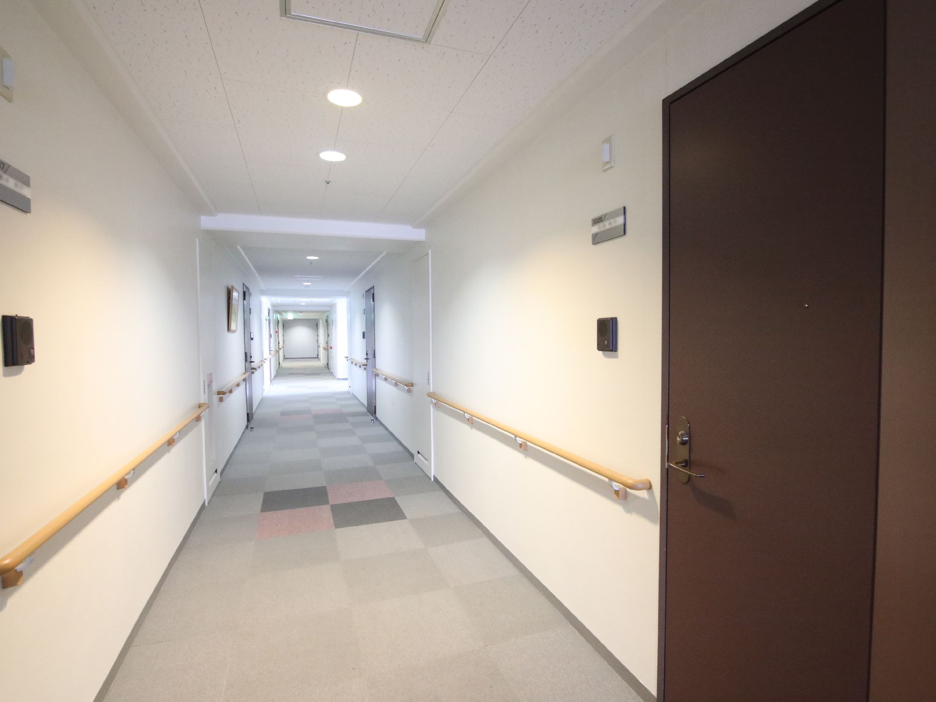 両側の白い壁に木製の手すりが付いた直線の廊下