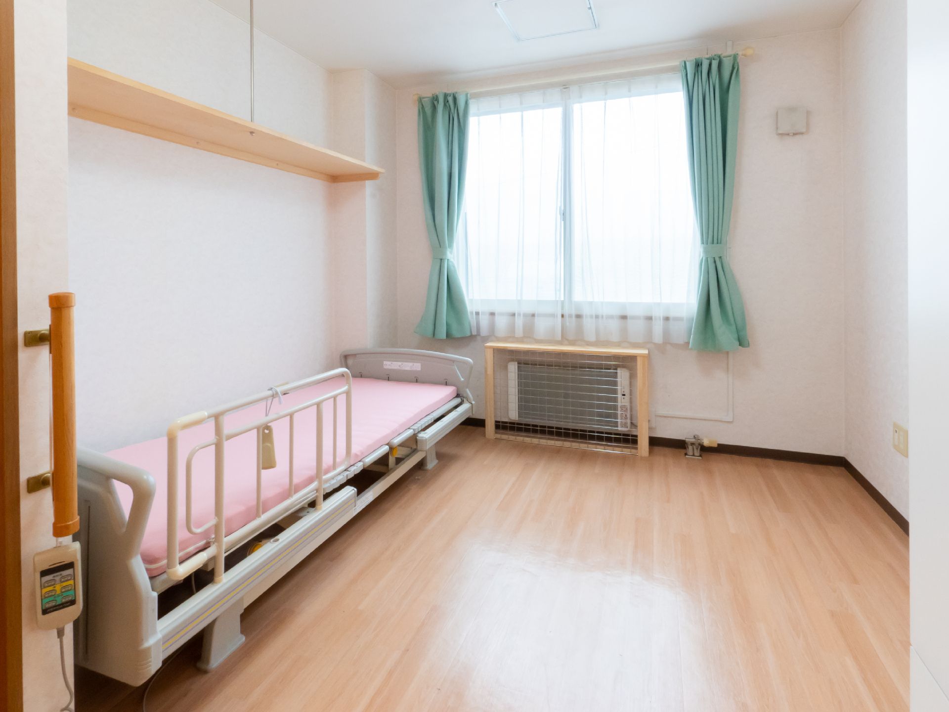 水の入ったコップを持って微笑むエプロンを付けた女性スタッフと薬を飲もうとしている高齢女性。