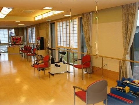 ゲーム用機器や運動機器などが、障子調の日よけが付いた窓際に並べられた広い部屋