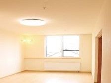 照明がついた窓があるワンルームの部屋。日差しが奥まで差し込む明るい空間
