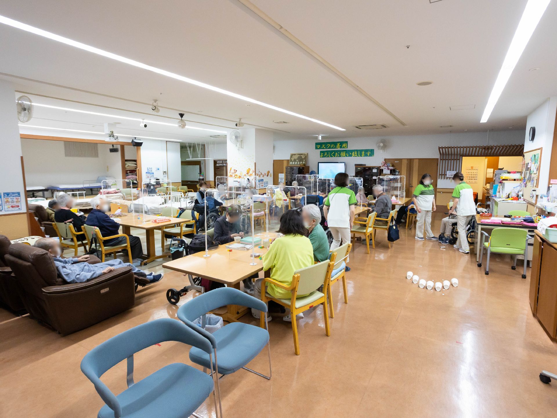 ブラウンのテーブルに職員と入居者が集まって談話を楽しんでいる。