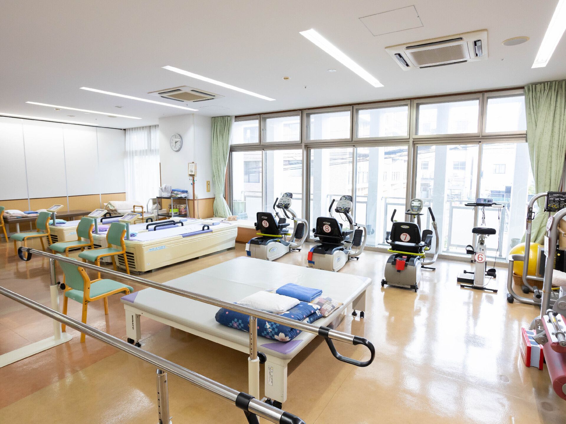 白いシャツを着た高齢男性が座ろうとしているところを介助に当たっているボーダー柄のエプロンを付けた若い女性スタッフ。