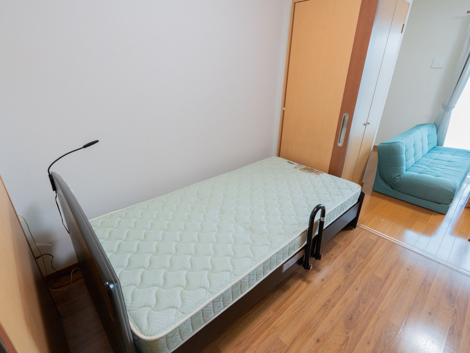 緑の多い屋外で笑顔で過ごしている車いすの高齢女性と付き添いの若い女性スタッフ。