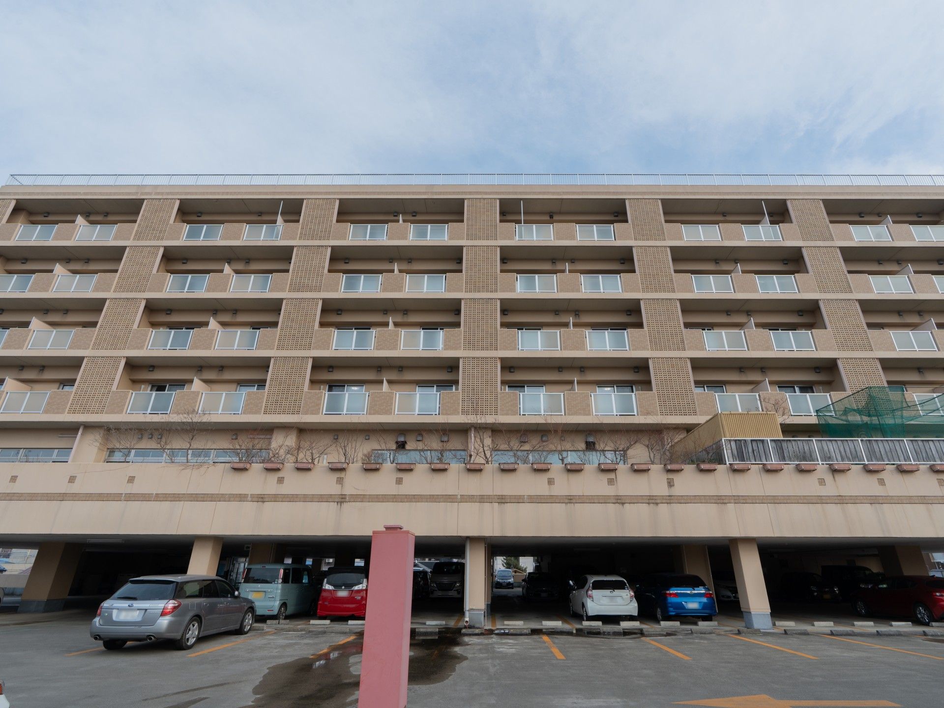 屋外で笑顔で過ごしている車いすの高齢女性と付き添いの高齢男性。両サイドには若い男女のスタッフがいる。