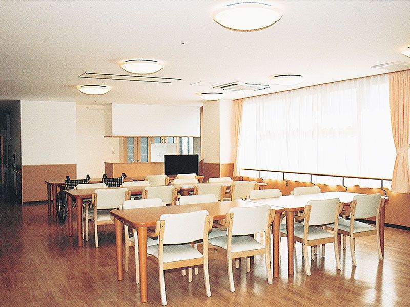 白い椅子がセットされた木製のテーブルが複数置かれたリビングダイニングには大きな窓が付いている。