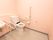 淡いピンク色の壁紙が施された広いトイレスペースに、蓋の付いていない洋式便器が据えられている。壁面に手すりとナースコールがある。