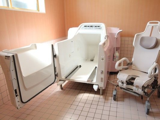 ピンクと白の機械浴槽が置かれた浴室には大きな窓もあり、体の状態に合わせて入浴ができる。