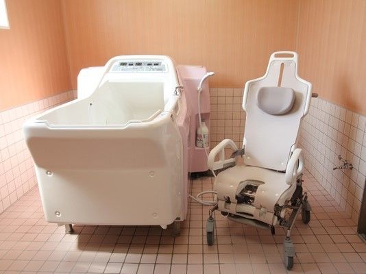 機械浴室が設置された浴室。白いタイルと木目調の壁を基調とした清潔感のある造り。