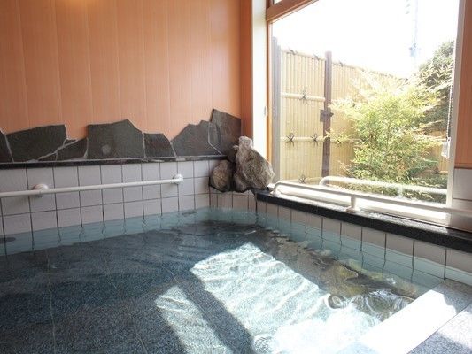 大きな浴槽が設置された浴室。浴槽の入り口と周囲には白い手すりが付いている。