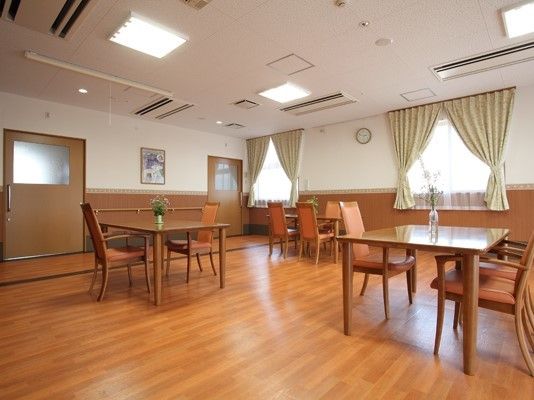 木製のダイニングテーブルが置かれ、ぬくもりが感じられる館内。絵画が設置されている。
