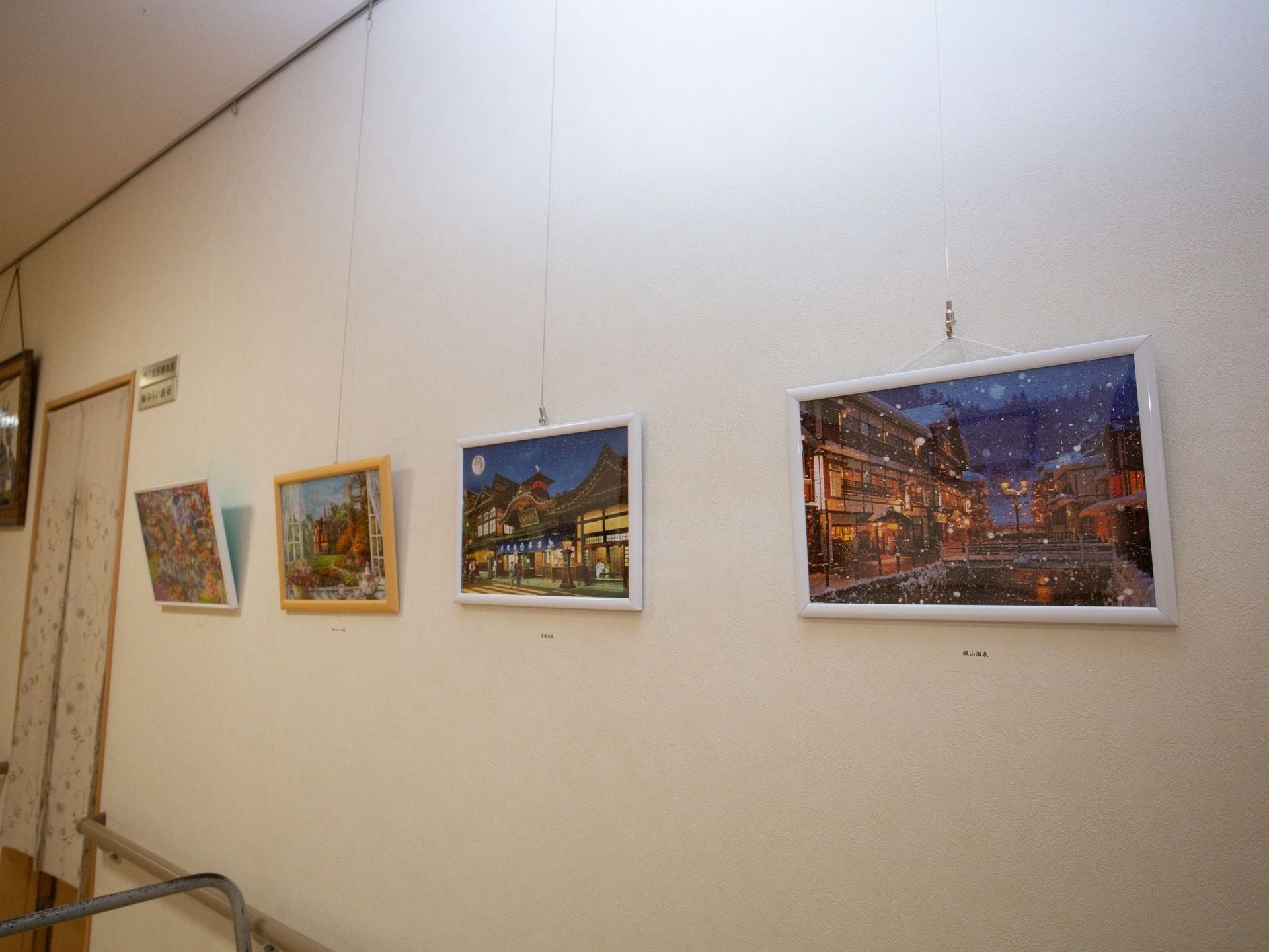 白い壁に、何枚か絵画が飾られている。そのうちの１枚は雪の風景である。ドアの前にのれんがかかっている。