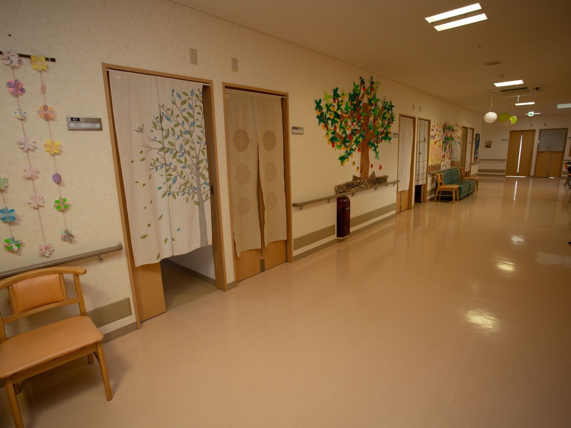 右奥に向かって廊下が伸びている。左手の壁にはのれんがかけられた入口が並び、壁にはたくさんの作品が飾られている。