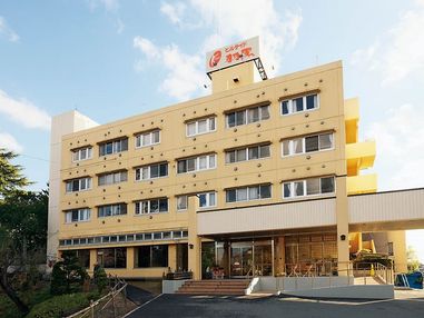 ４階建てでクリーム色の建物。玄関までは手すり付きの階段とスロープがある。玄関前には鉢植えが置かれ、ひさしが付いている。