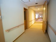 通路の両脇の壁に手すりが備わっている。通路の奥には食堂があり、テーブルや椅子が置かれているのが見える。