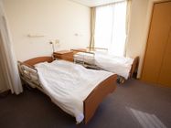 小さな収納家具を挟んでベッドが二台置かれており、壁際にクローゼットが設置されている。ベッドの間には、ナースコールが備わっている。