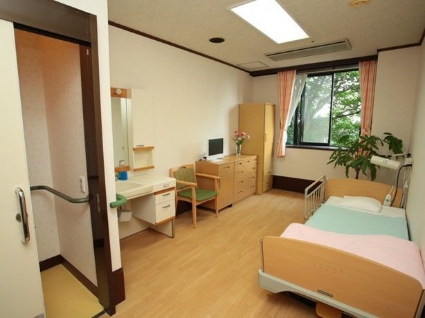 収納やテーブル、いすなどがある小さなワンルームの様子。引き戸式の手すり付きトイレもある