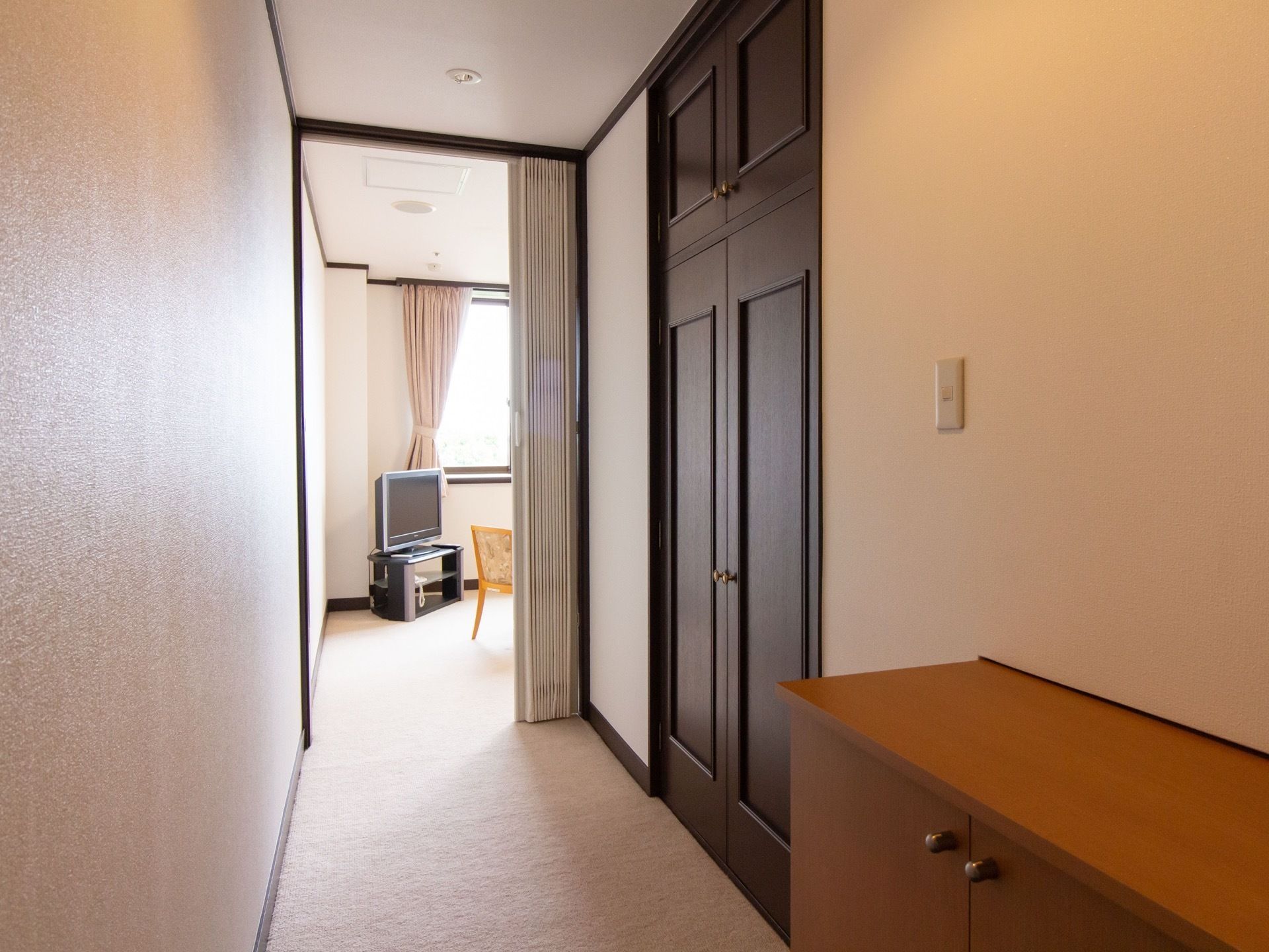 手前の通路から奧の部屋まで、床にカーペットが敷かれており、アコーディオンカーテンが取り付けられている。
