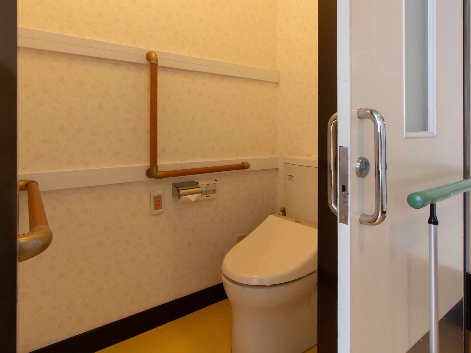 引き戸の奥にトイレスペースがあり、洋式便器が据えてある。出入り口付近や便器の奧の壁面に手すりが施されている。
