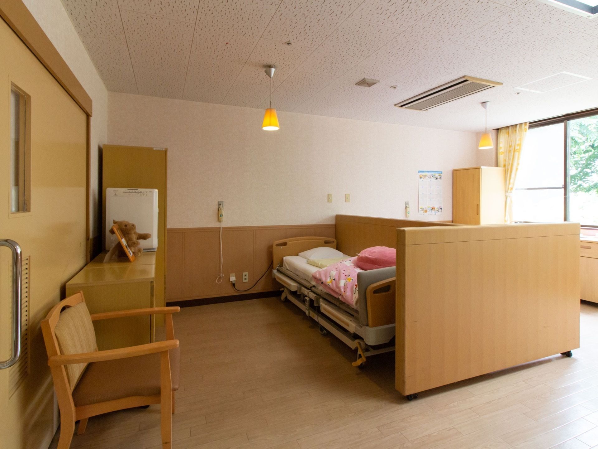 床や壁面、扉などに木目調の部材が採用されており、木の温もりを感じられる室内である。窓の外に木々の緑が見える。