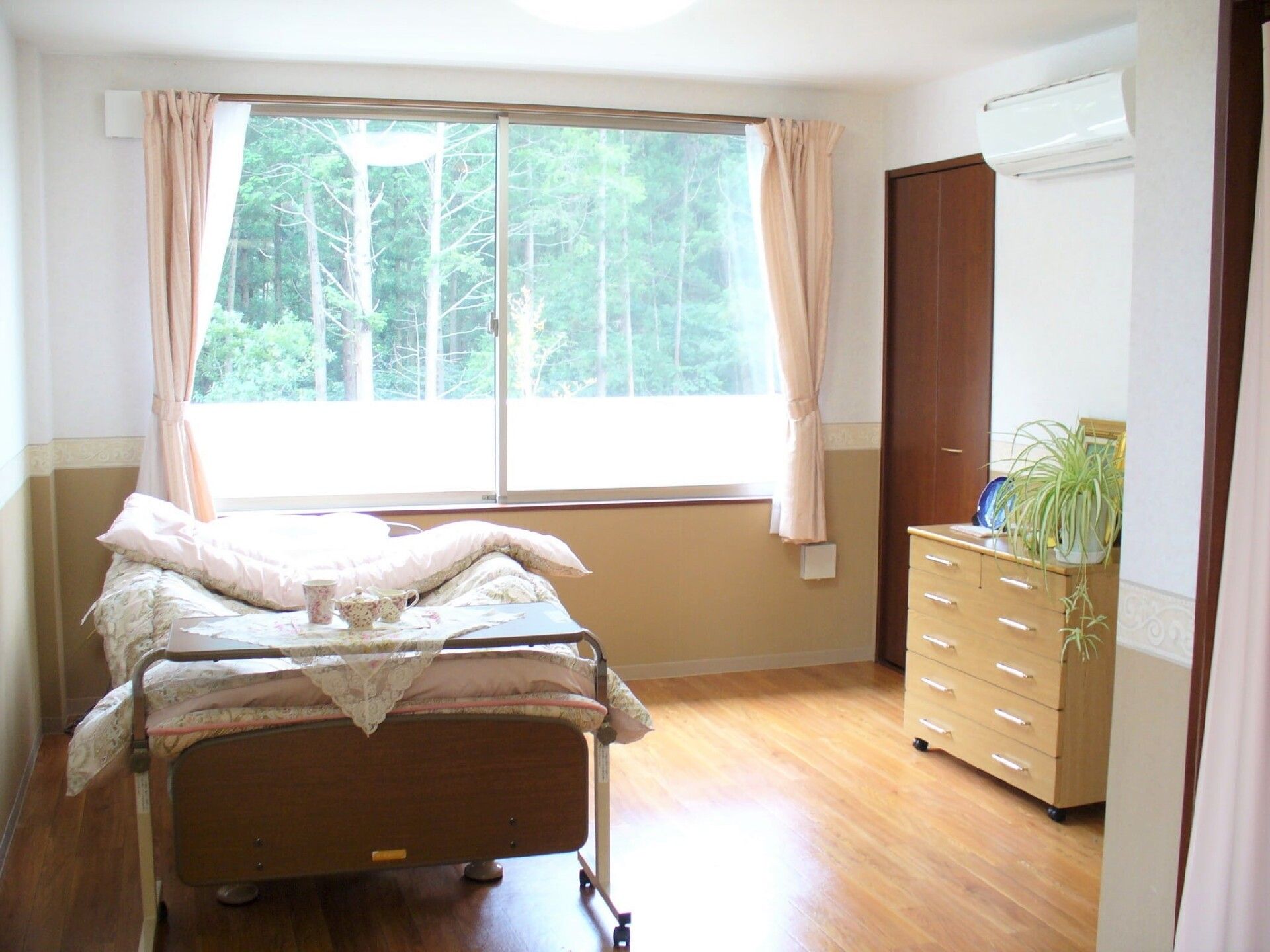 介護仕様のベッドとタンスなどが置かれている小さなワンルームタイプの部屋