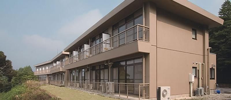 建物周辺は自然豊かな木々。落ち着いた色合いの建物