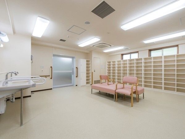 広い脱衣所にはたくさんの棚が設置され、中央にいすが置かれている。車いす対応の洗面所もある。