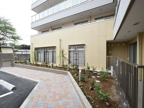 玄関までのアプローチはカラフルなレンガで、それに沿うようにして花が植えられている花壇がある。