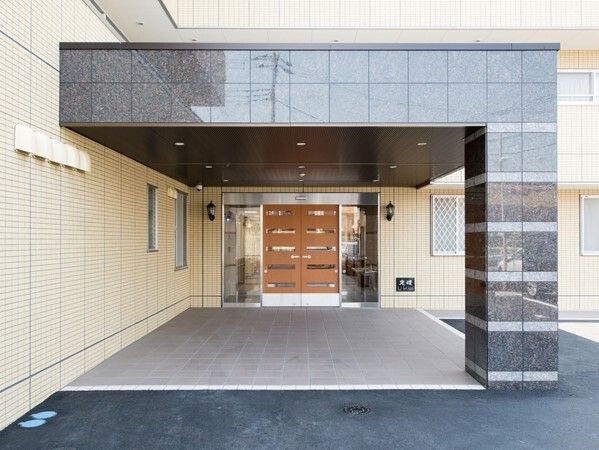 大きな車寄せが付いた玄関。玄関までのアプローチが長く、ブラウンのどっしりとしたドアが付いている。
