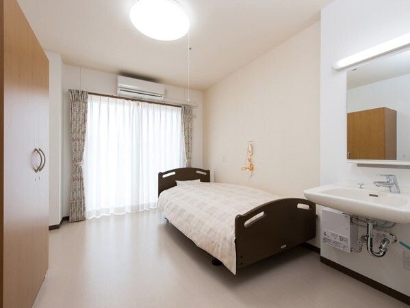 寝具付きのベッドが置かれ、緊急通報装置が付いた部屋には車いす対応の洗面所がある。