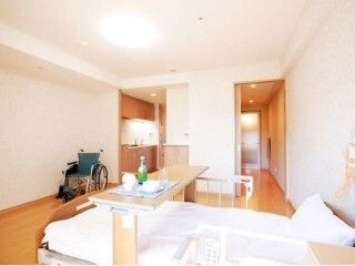 寝具付きのベッドが置かれたフローリングの部屋。ベッドサイドには緊急通報装置がある。