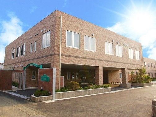 2階建ての高齢者施設外観。建物の前に花壇が設けられている。