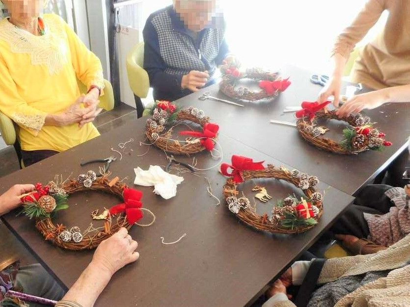 季節に合わせたリースを作っている高齢者の様子。創作レクリエーションの一場面