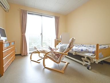 介護用ベッドなどの家具が置かれた部屋で、椅子に座りくつろぐ入居者様