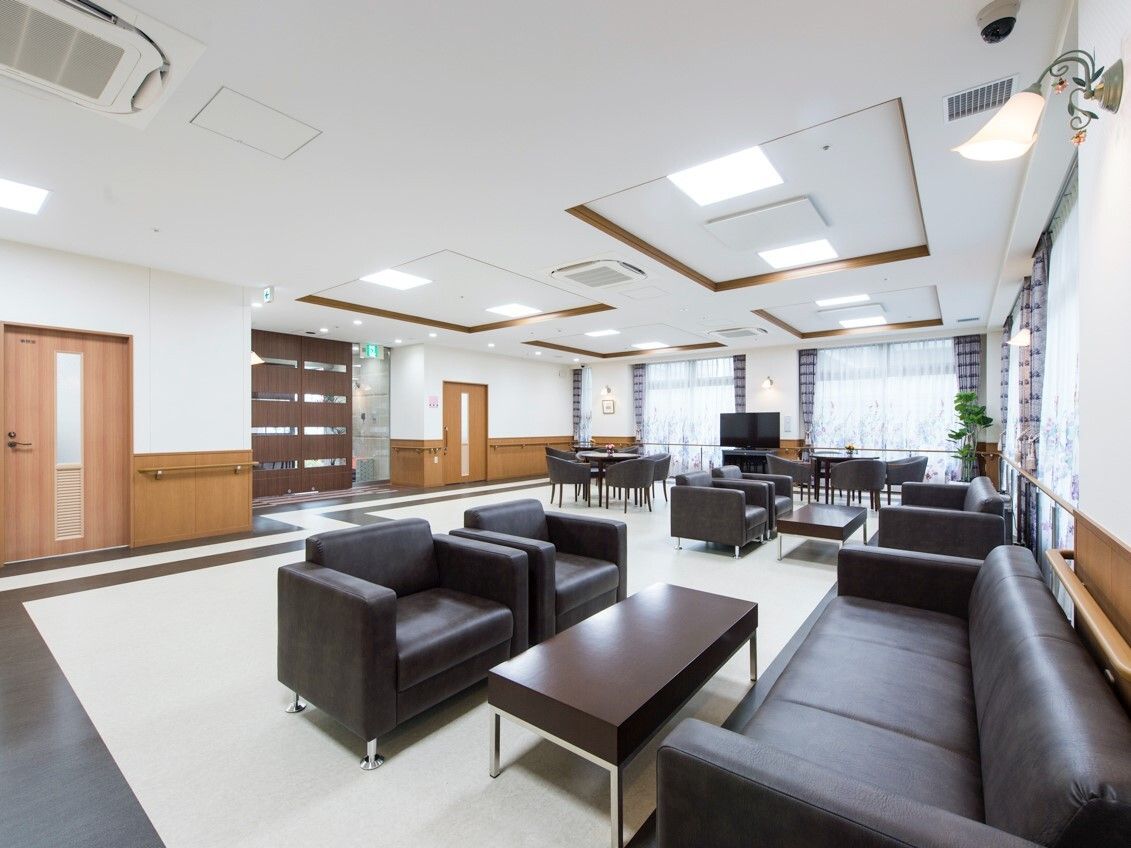 黒いどっしりとしたソファの応接セットが複数置かれた共有スペース。エントランスのドアが左側にある。