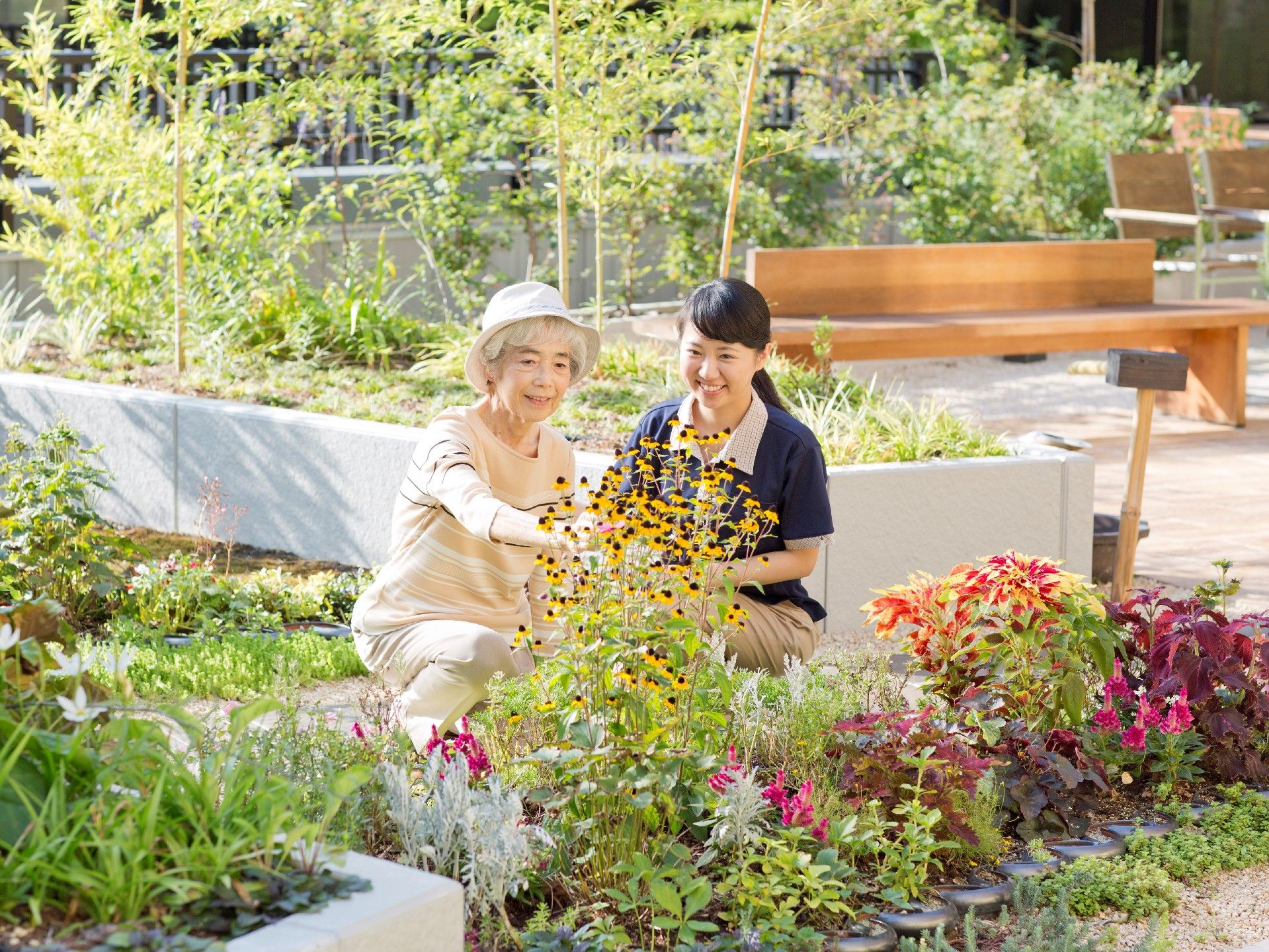 花壇に色とりどりの花が植えられている。奥には木製のベンチが見える