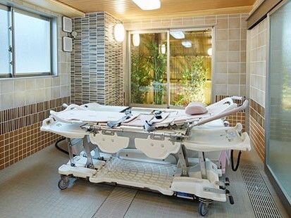 寝たまま入浴可能な寝台浴が置かれた浴室。デザイン性の高い壁がおしゃれ。窓の外にはライトアップされた坪庭もある。