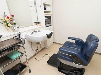 洗髪台の前には理美容室用の椅子があり、壁には鏡も設置され、花も飾られている。