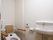 温水便座が設置されたトイレ。左側には手洗い場や手すりがあり、トイレットペーパーホルダーには手すり代わりともなる棚もある。