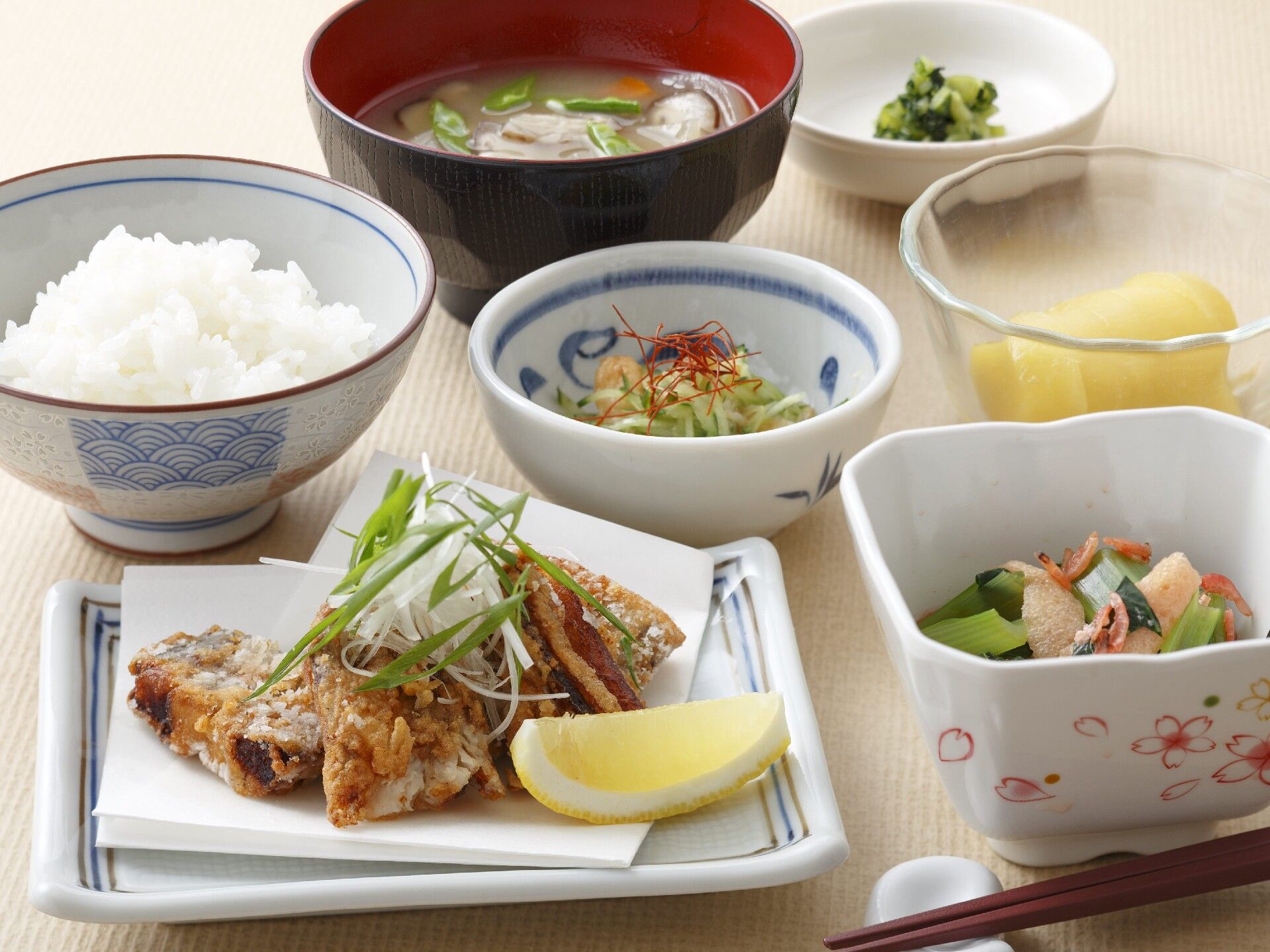 白いご飯に味噌汁、野菜の小鉢が数種類、メインのレモンが添えられた魚の竜田揚げのようなものがある。