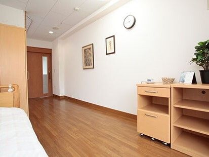 寝具付きのベッドや時計、絵画などが飾られたフローリングの部屋には収納家具もあり、観葉植物も飾られている。