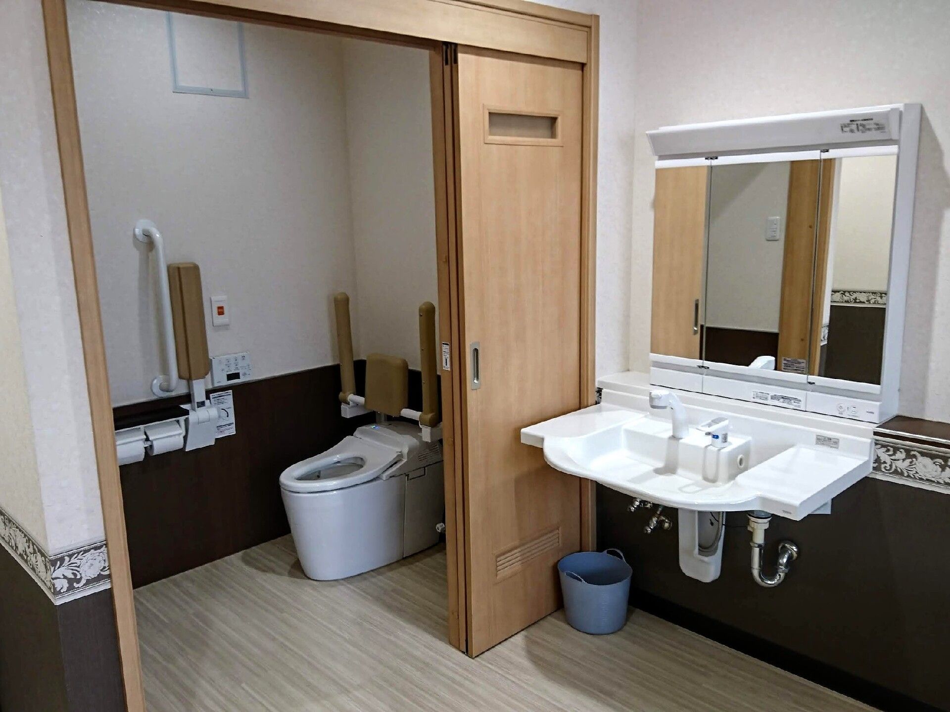 トイレには引き戸があり、背もたれや手すりが付いた便座が設置されている。トイレをだたとことには鏡付きのワイドタイプの洗面所もある。