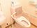 トイレには背もたれと手すりが付いた便座が付いていて横には手洗い場があり、壁には操作ボタンがある。