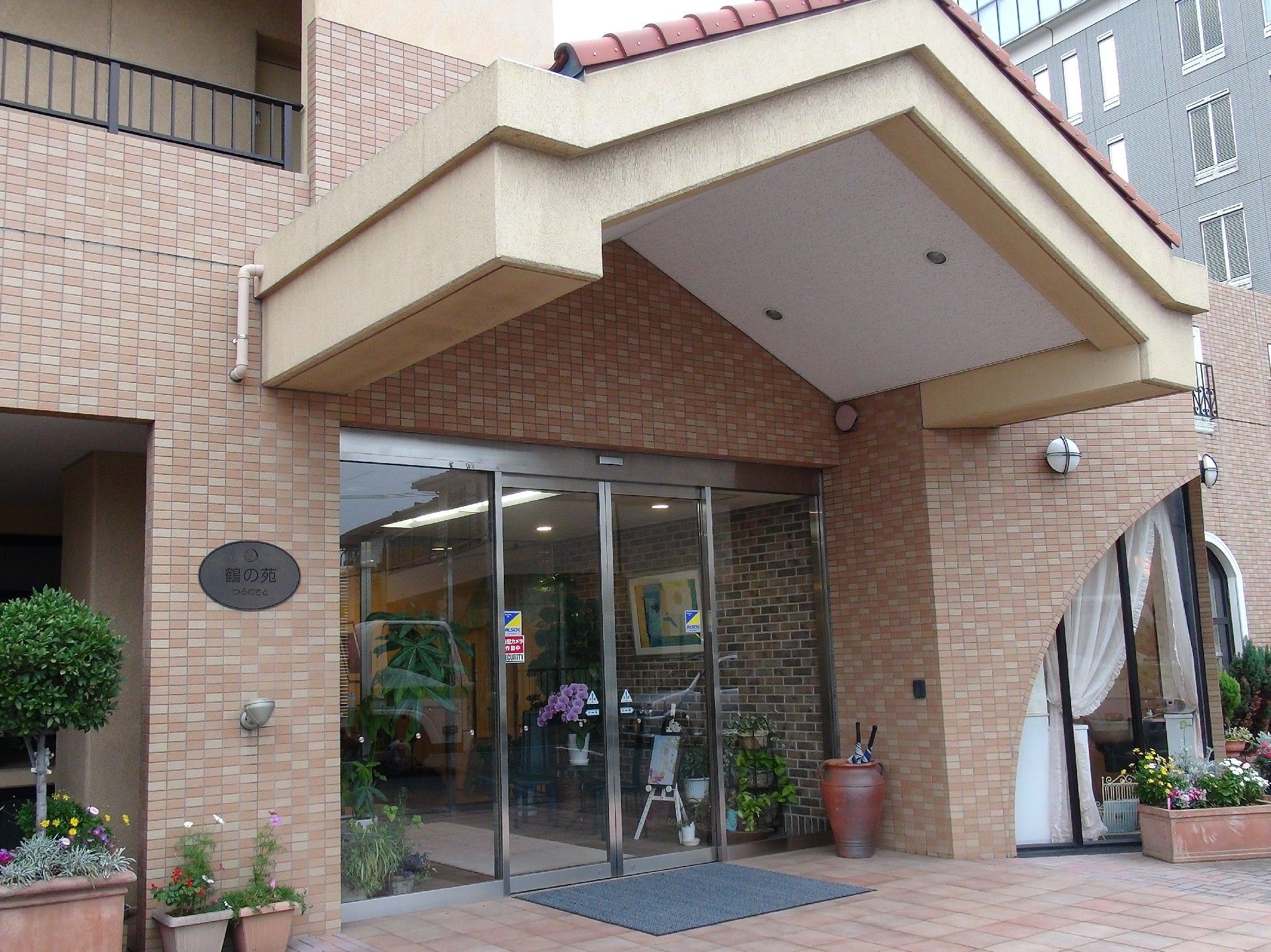 レンガ調の外壁が印象的な建物。建物周辺にはたくさんの鉢植えも置かれている。