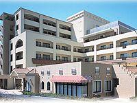 ブラウン系でまとめられたどっしりとした建物の周りには季節の木や花がきれいに置かれている。