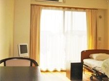 薄型テレビとベッド、いす、テーブルがある小さな部屋の様子