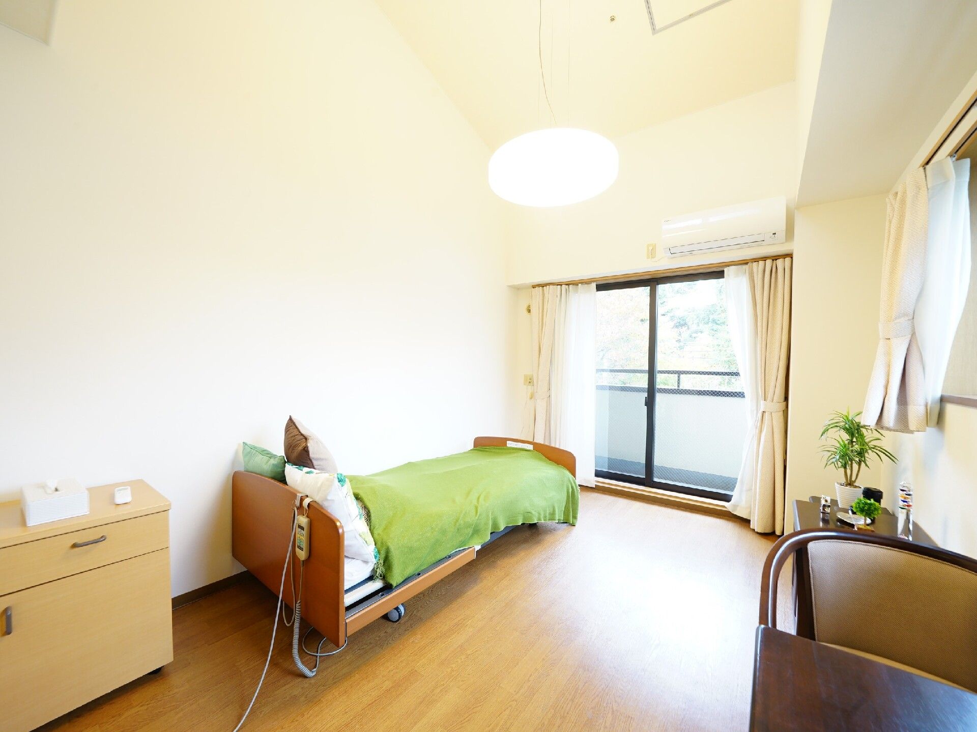 介護用ベッドのほか、家具としてテーブルセットや棚を置いた部屋