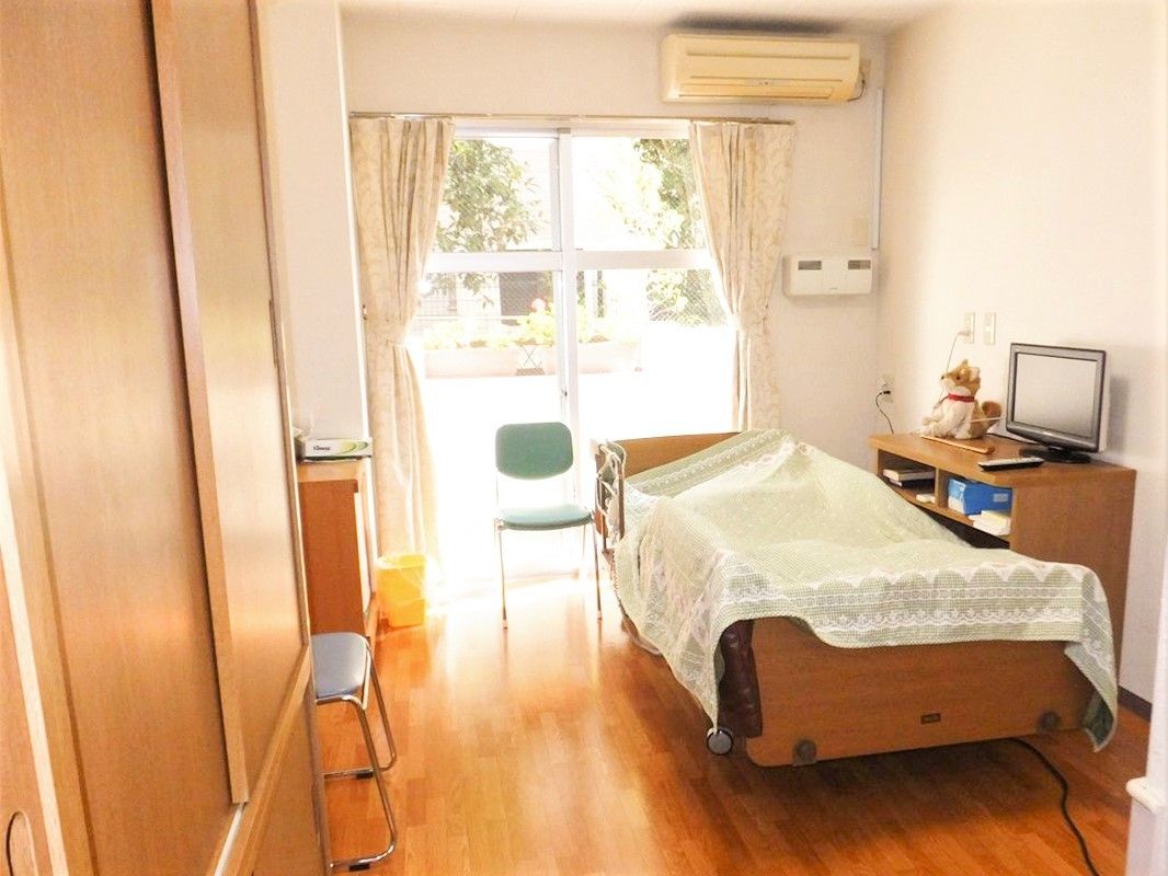 収納付きの個室の部屋。寝具付きベッドやテレビ、エアコンなどが置かれている。