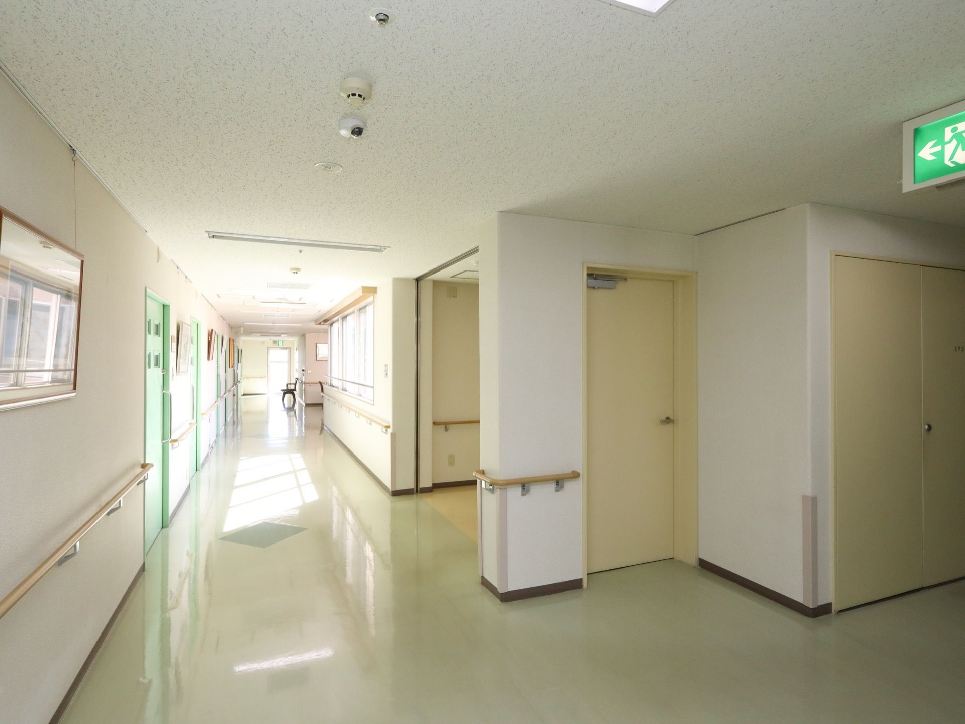 廊下には、防火扉やスプリンクラーなどの防火設備が設置されている。樹脂素材製の床は清潔に保たれており、余計なものは置かれていない。