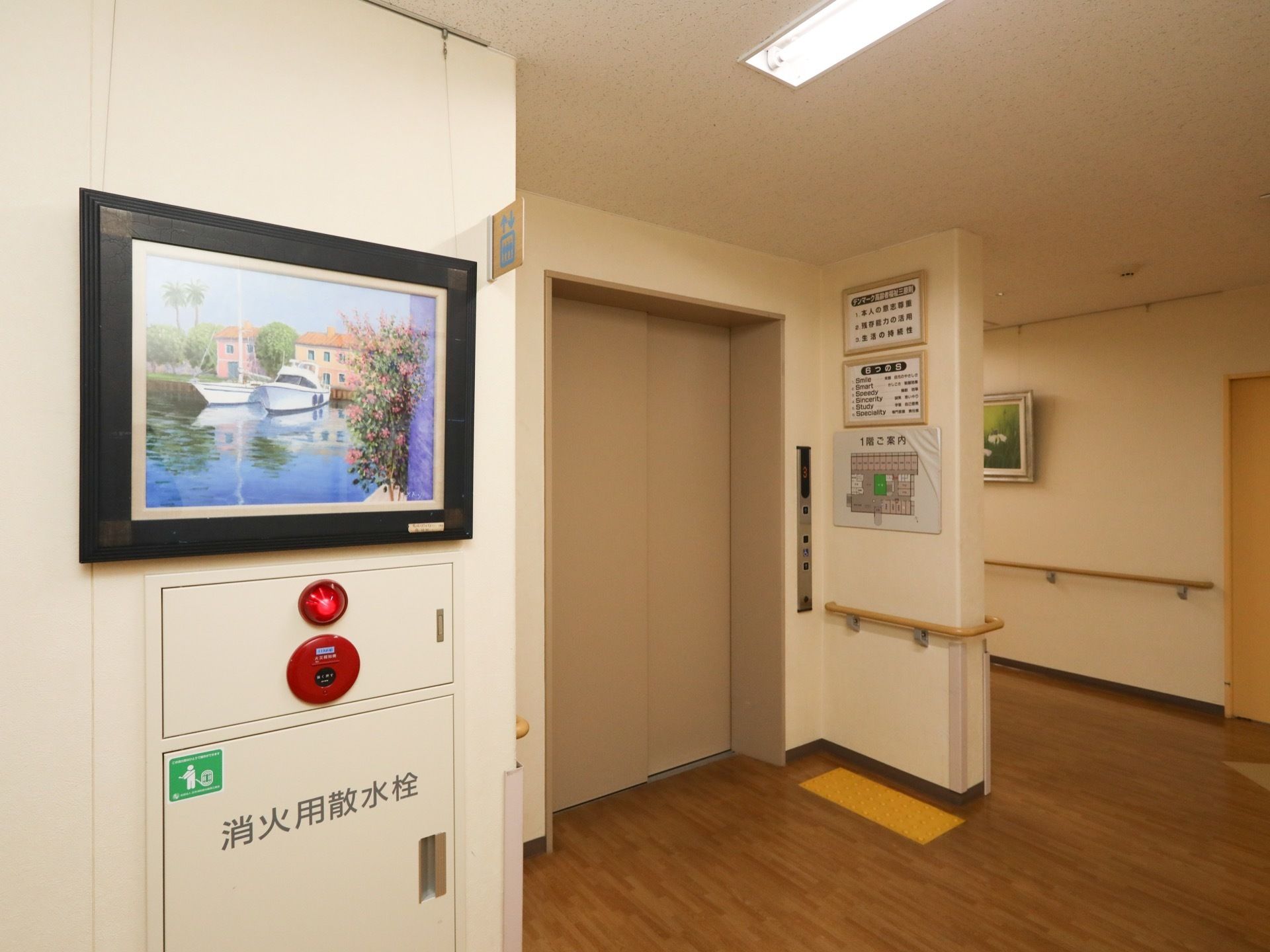 廊下の一画がエレベーターホールになっている。エレベーターの位置はピクトグラムで表示されている。扉前には点字ブロックが設置されている。